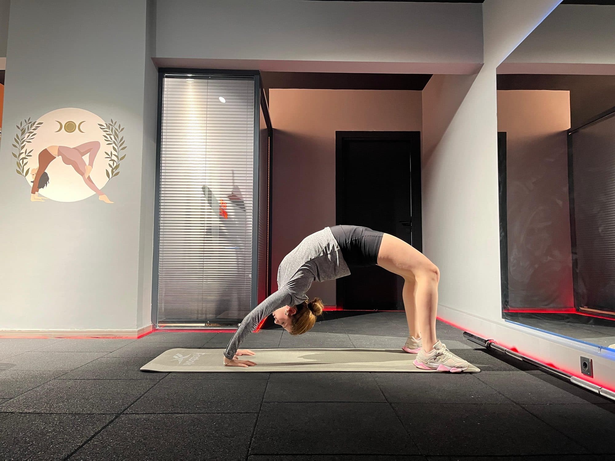 Pilates stüdyosunda mat üzerinde tam köprü pozisyonunda vücudunu yay gibi geren kadın